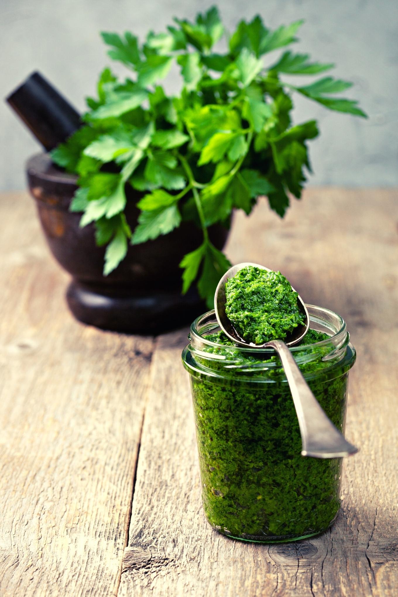lemon parsley pesto in a jar with a spoon and parsley in the background